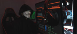 Masked hacker with computer screen showing "security alert."
